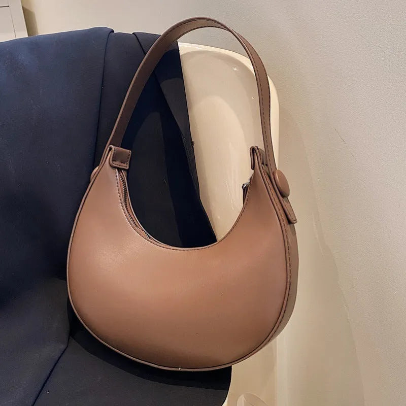 Women's retro dumpling-shaped PU leather shoulder bag in black showing sandwich pockets and zippered compartment