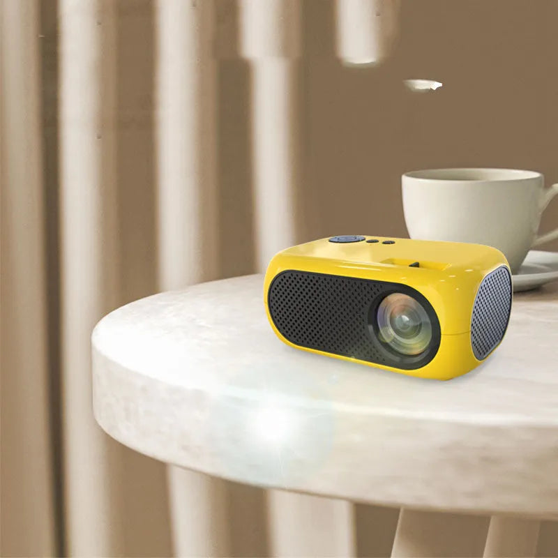 M24 gold and white micro mini portable LED projector with power adapter and AV cable on a grey background