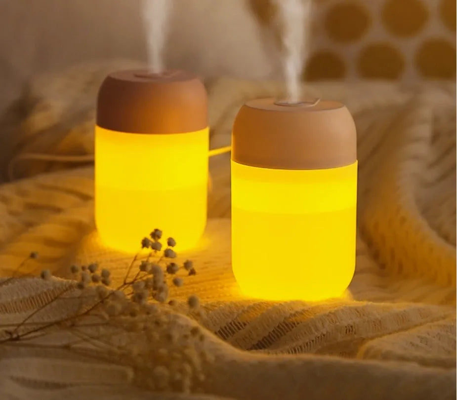 White cylindrical USB-powered mini humidifier with aromatherapy function on a desk.