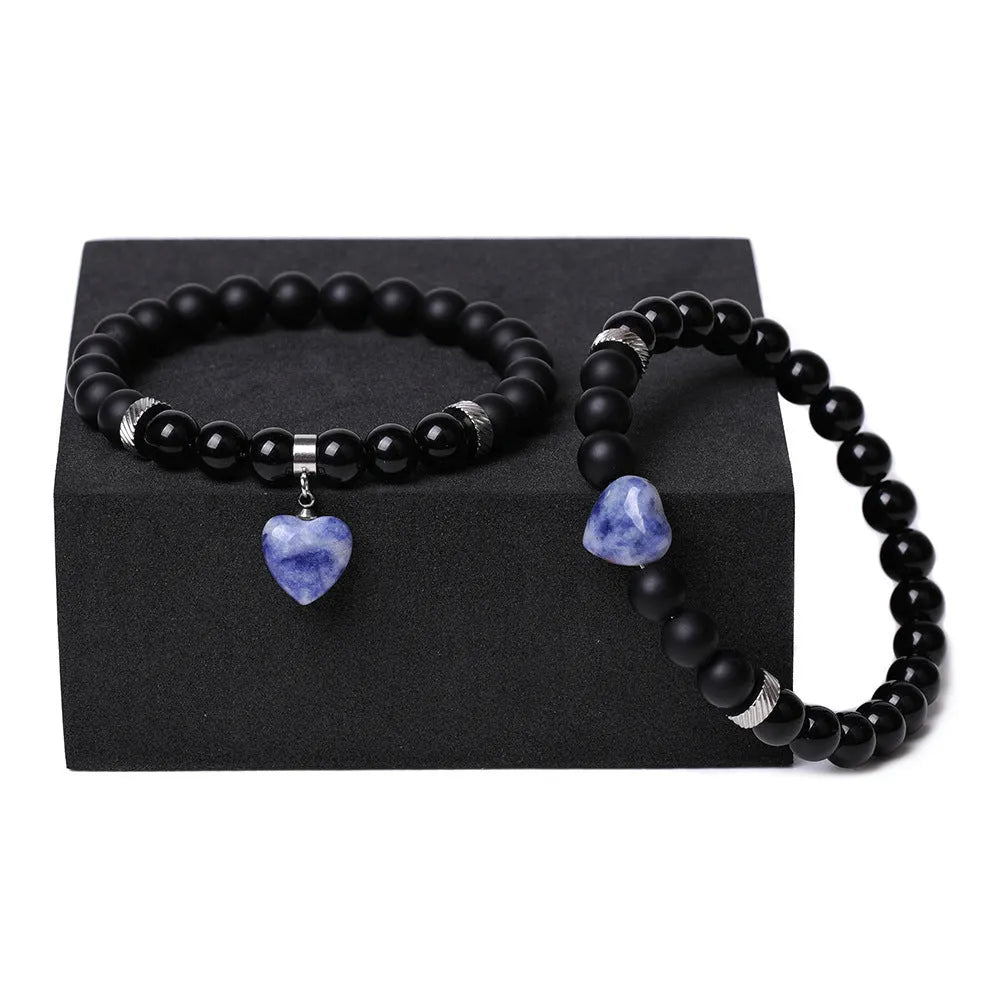 A pair of matching bracelets with polished geometric heart pendants made from natural stone.