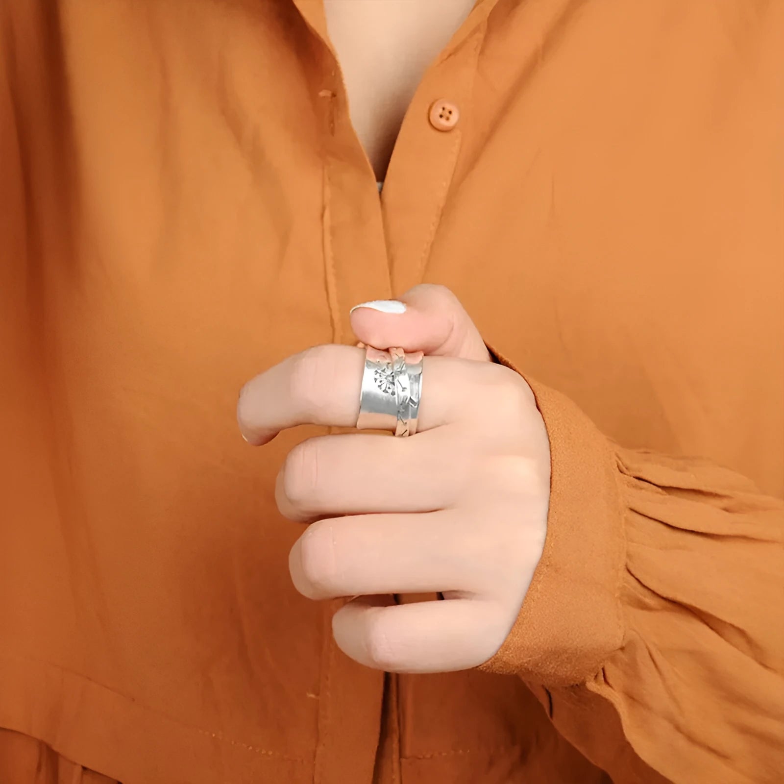 Silver-coloured rotatable flower ring on a finger, showing the floral detail.