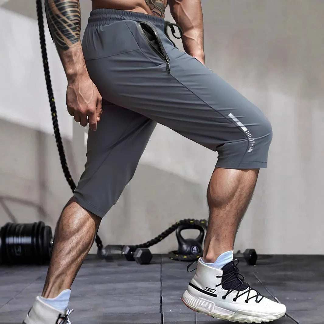 Man wearing grey cropped ice silk sports pants made from quick-dry nylon fabric.