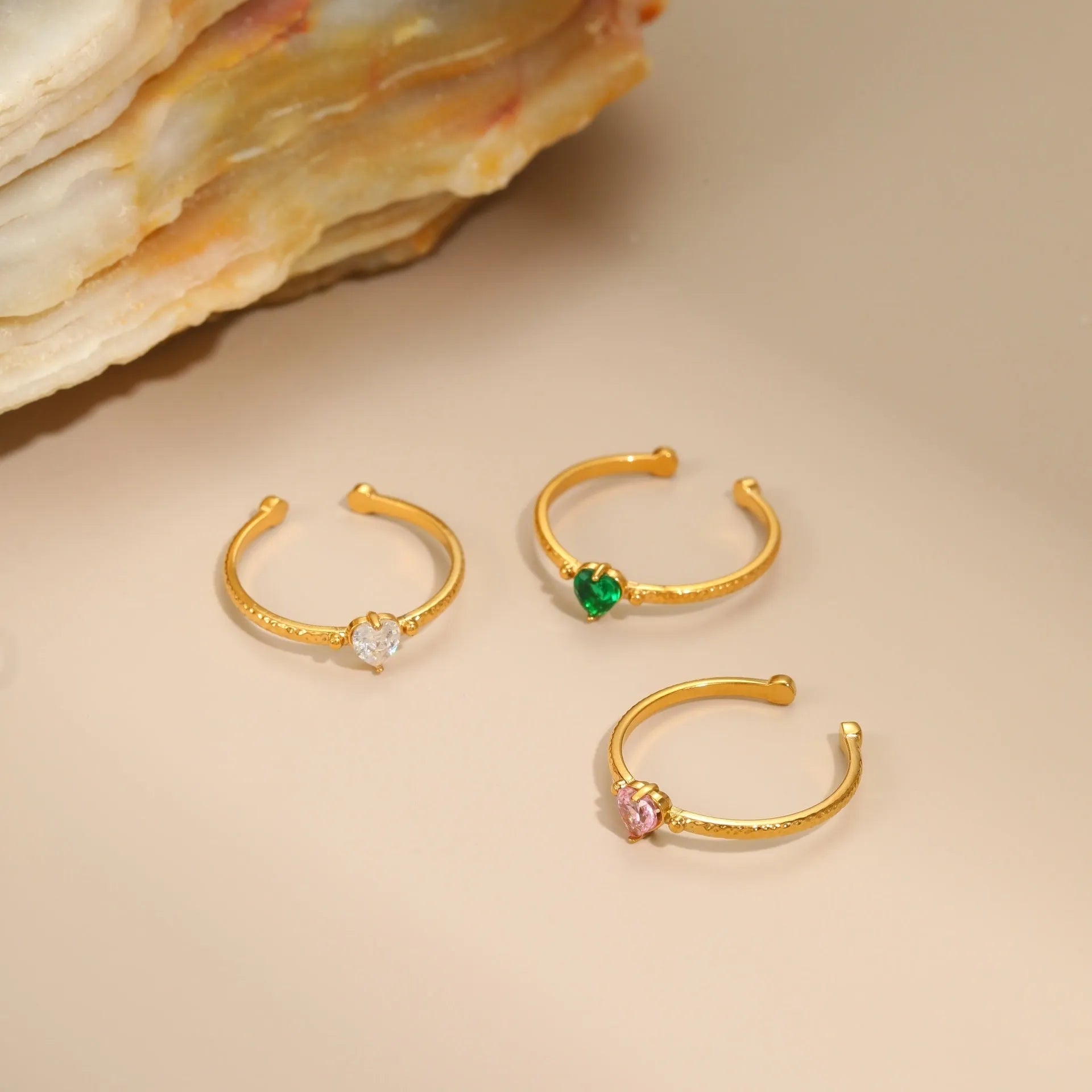 Open-ended stainless steel ring with a geometric heart shape and inlaid green zircon stone.