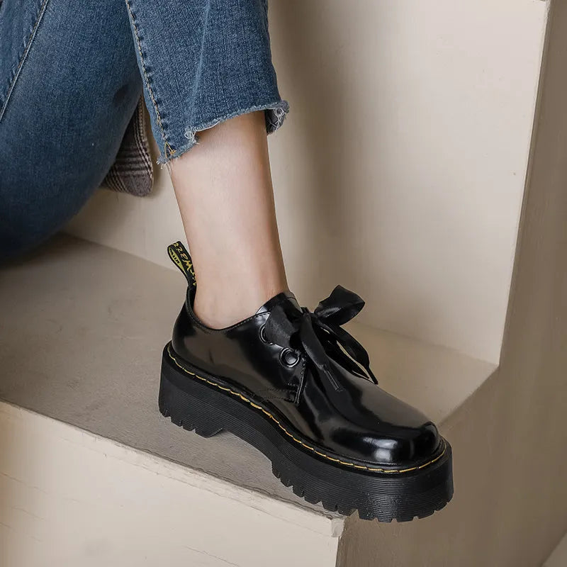 Women's black leather shoes with thick soles, ribbon cross straps, and lacing closure