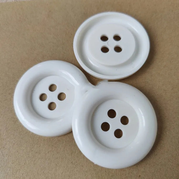 Assortment of oversized round plastic buttons in various colours with four holes.