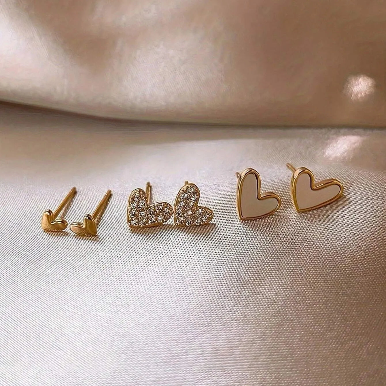 Women's heart-shaped earring set with three pairs in gold, black, black and white, and pink electroplated colours