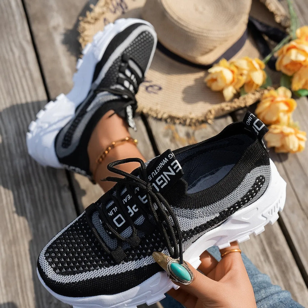 Women's lace-up Flyknit mesh sneakers in a grey colour combination with a round toe and flat rubber sole.