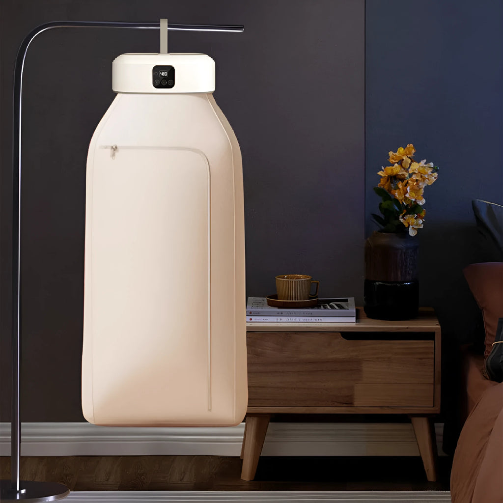 White cylindrical compact foldable laundry dryer with remote control on a table.