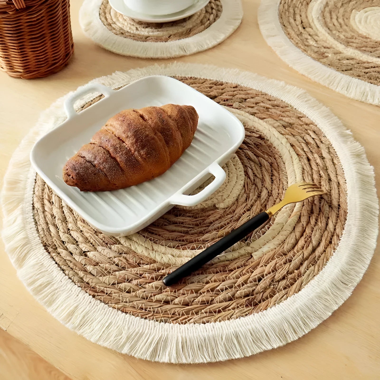 Round Japanese straw placemat with corn rope tassel detailing on wooden table