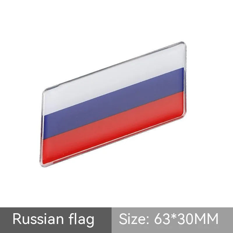 Aluminium parallelogram car sticker showing a national flag design, measuring 6.3 by 3 centimetres.