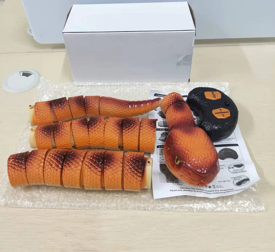 Smart sensing interactive electronic snake cat toy on a floor, showing segmented plastic body and USB charging port.
