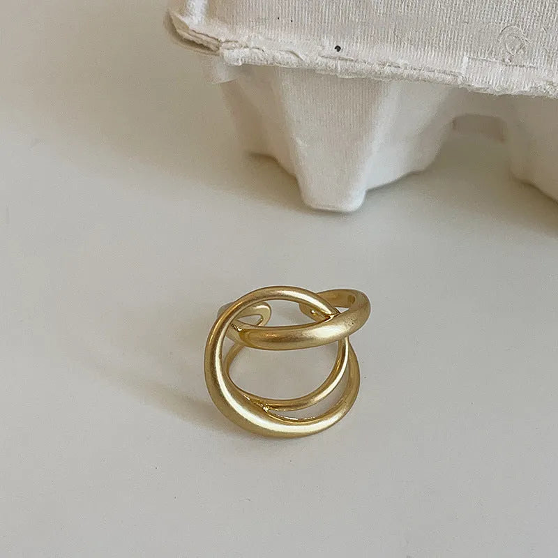 Geometric open ring with three-dimensional interlaced metal design in gold or silver colour
