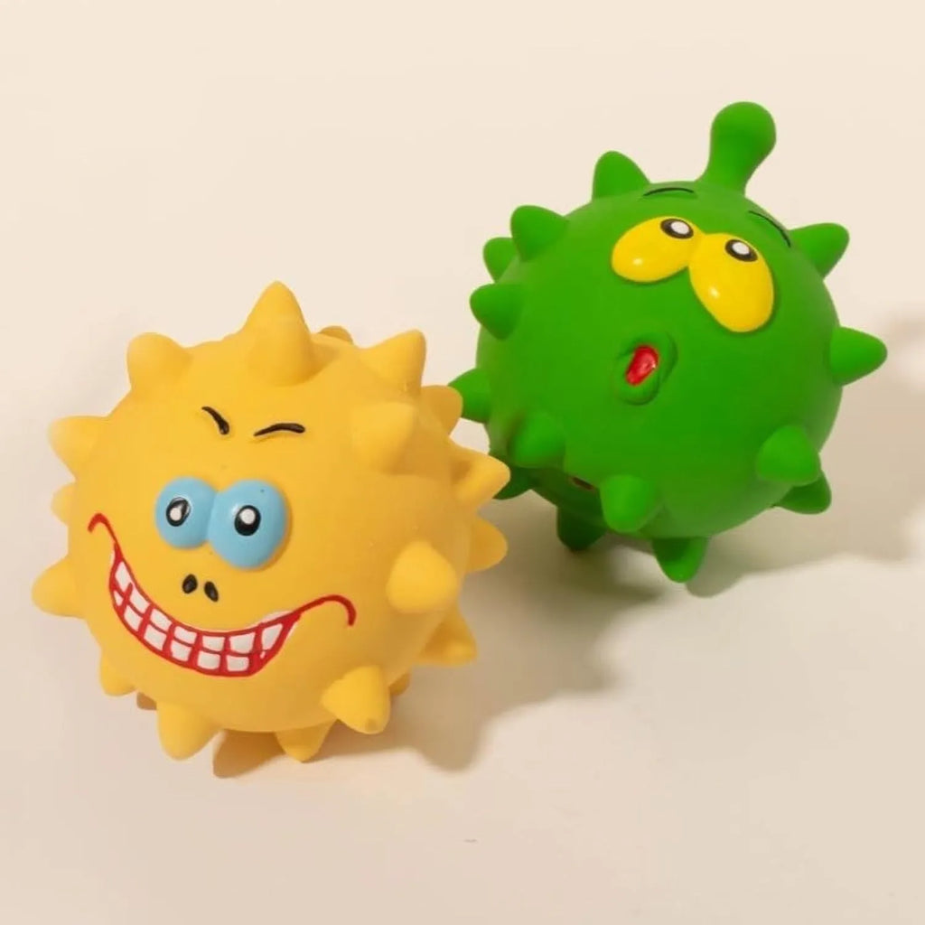 Set of four coloured latex squeaky dog balls with cute faces on a bumpy surface.