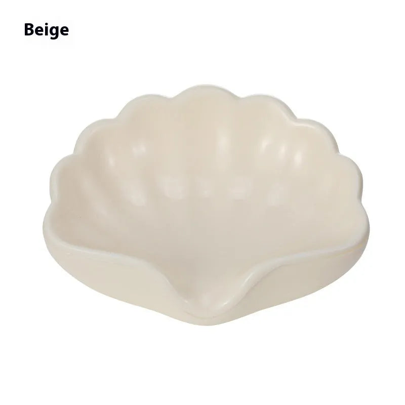 White or pink plastic shell-shaped soap dish with slatted base for bathroom use.