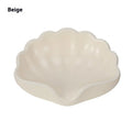 White or pink plastic shell-shaped soap dish with slatted base for bathroom use.