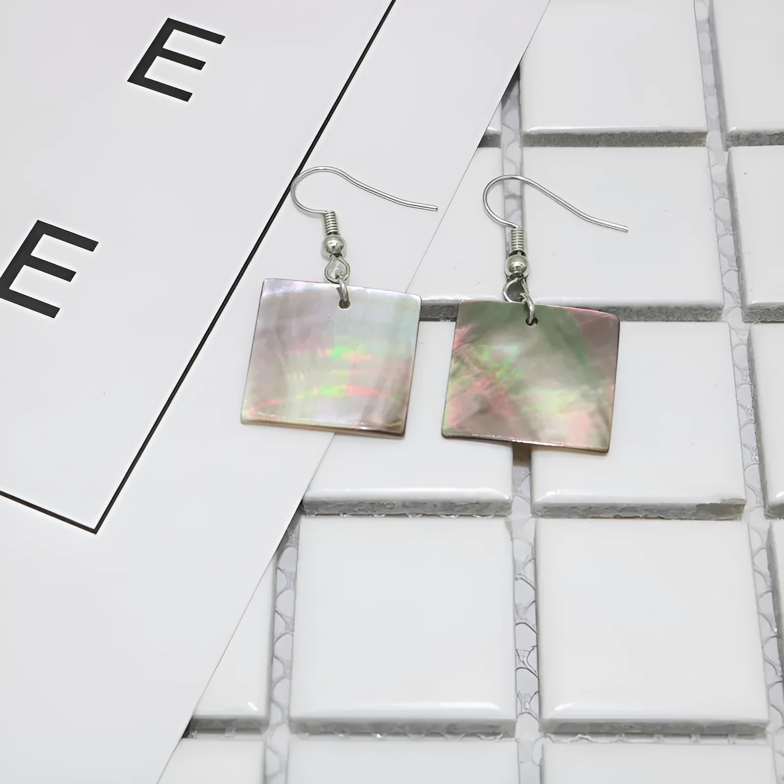 A pair of geometric-shaped earrings made from shell in a retro style, showing colour options.