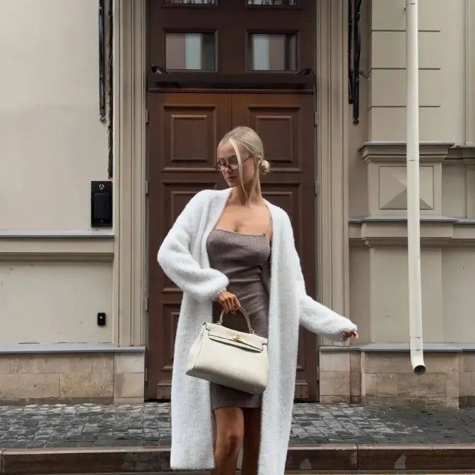 Long white knitted cardigan jacket with long sleeves on a hanger