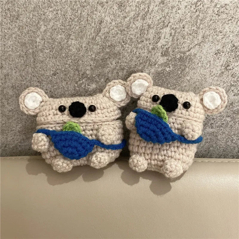 Handmade knitted koala bear backpack cover for Apple Airpods case on a table.
