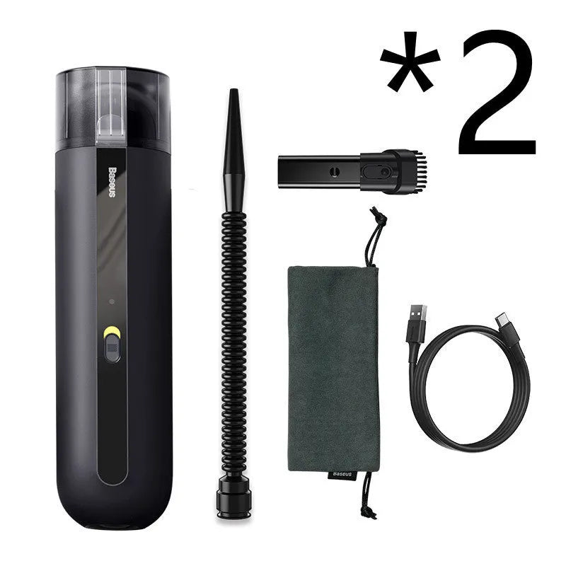 Black cordless handheld car vacuum cleaner with blowing hose attachment on a desktop.