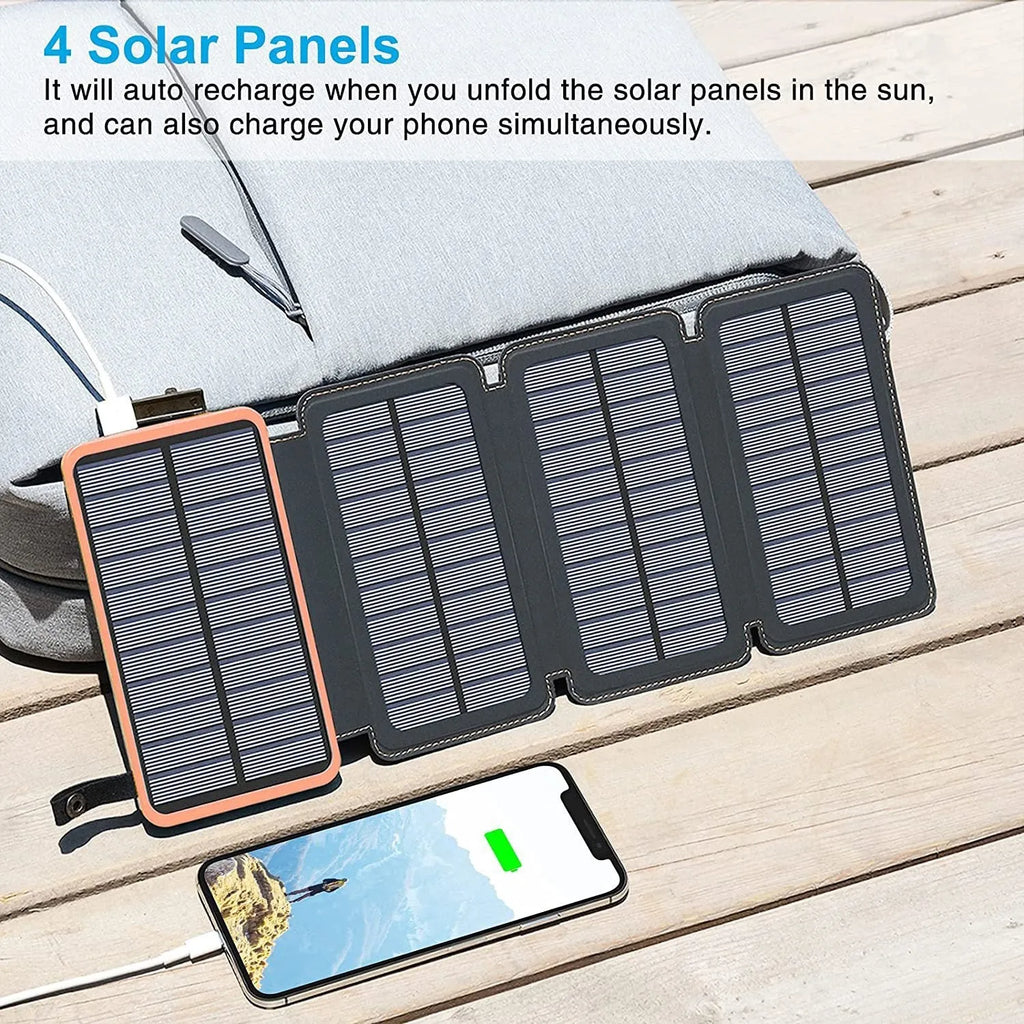 Black solar power bank with a solar panel, showing its USB ports and LED light, placed outdoors on a rock.