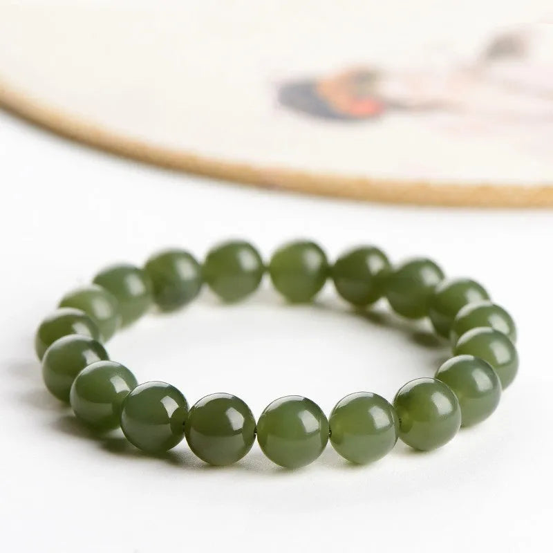 A polished Hetian Jade ball bracelet in a clear water colour on a wrist, showing spherical beads.