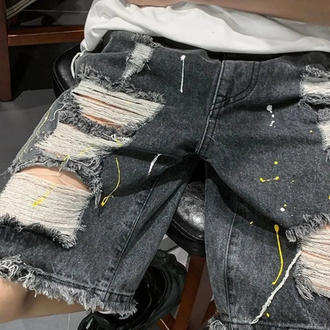 Man wearing loose-fit light blue denim shorts with water-washed distressed fabric and a fifth pants length.