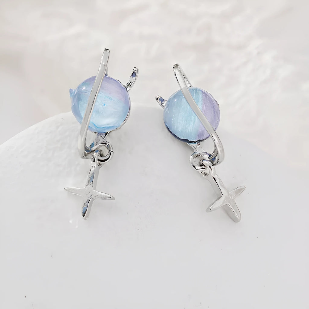 Metal geometric planet earrings in multicolour finish on a neutral background