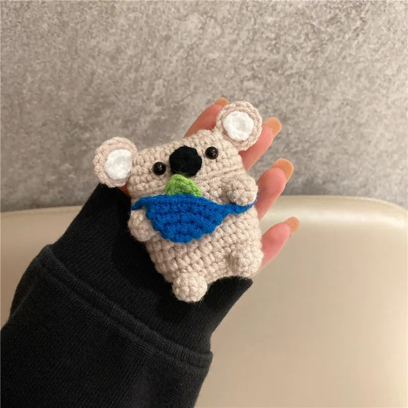 Handmade knitted koala bear backpack cover for Apple Airpods case on a table.