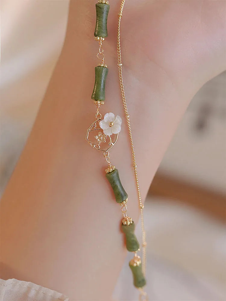 Natural olivine gemstone bracelet with double layers and twin Bells of Ireland charms on a wrist.