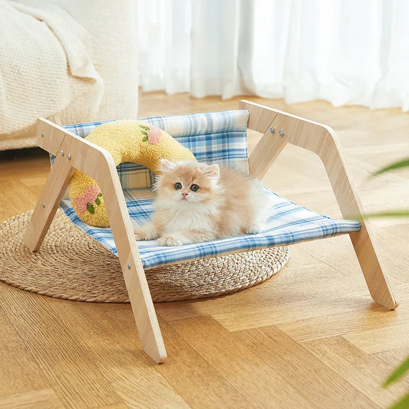 Blue elevated cat hammock bed with wooden beach chair frame on a white floor.