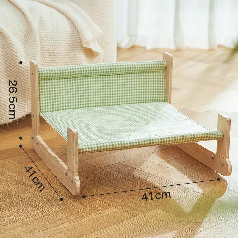 Blue elevated cat hammock bed with wooden beach chair frame on a white floor.