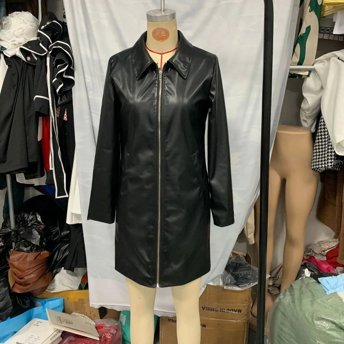 Women's black medium-length leather jacket with long sleeves on hanger
