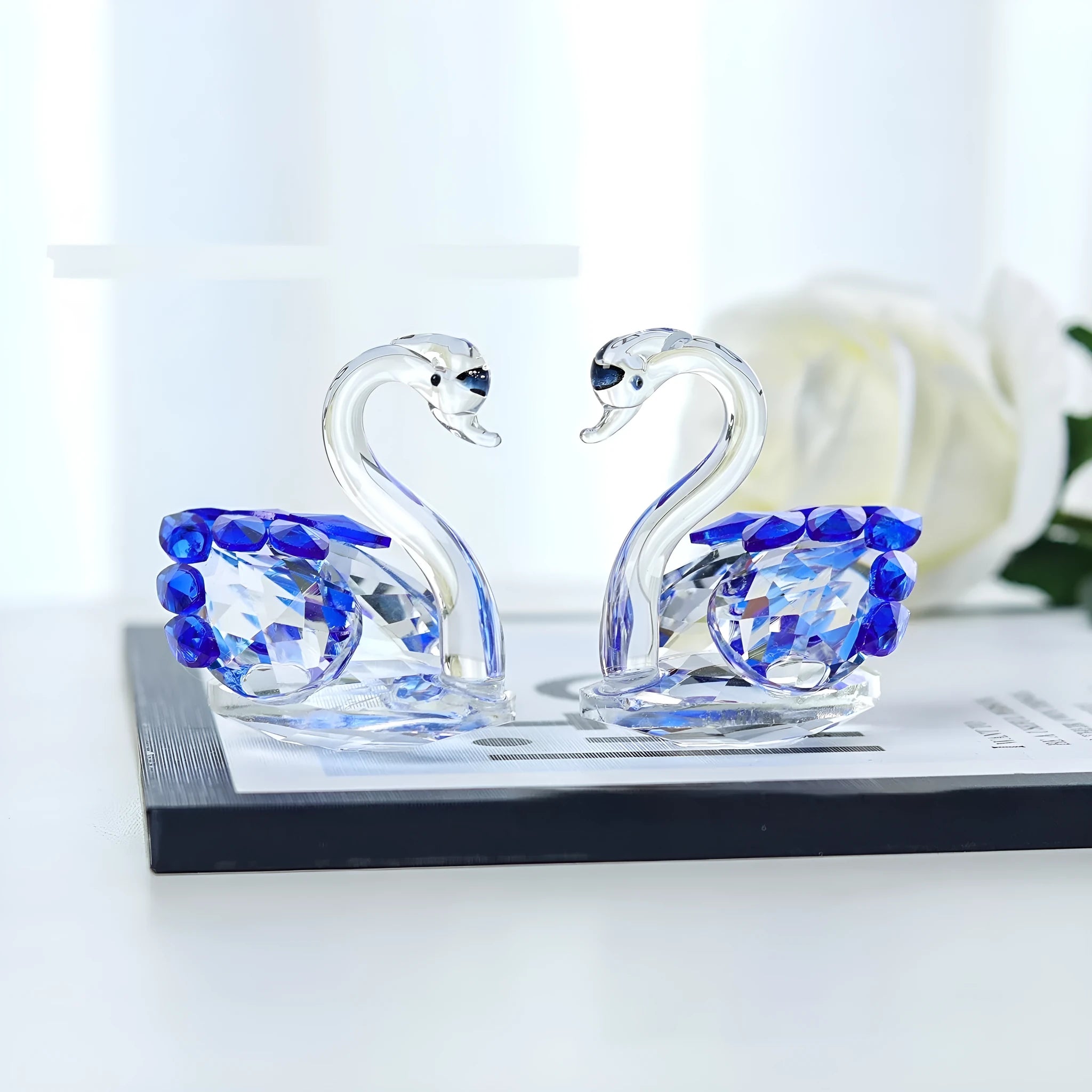 White crystal swan ornament on a desktop, shown in solid head and empty tube styles in red, blue, pink, and purple.