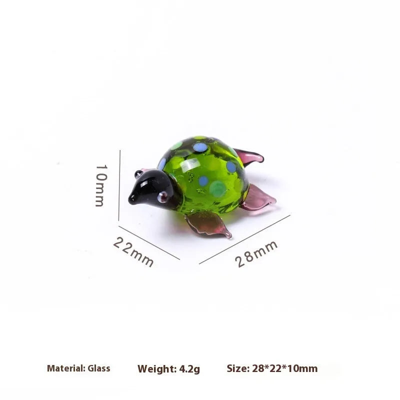 Geometric glass turtle ornament with a blue head and blue shell on a wooden desktop.