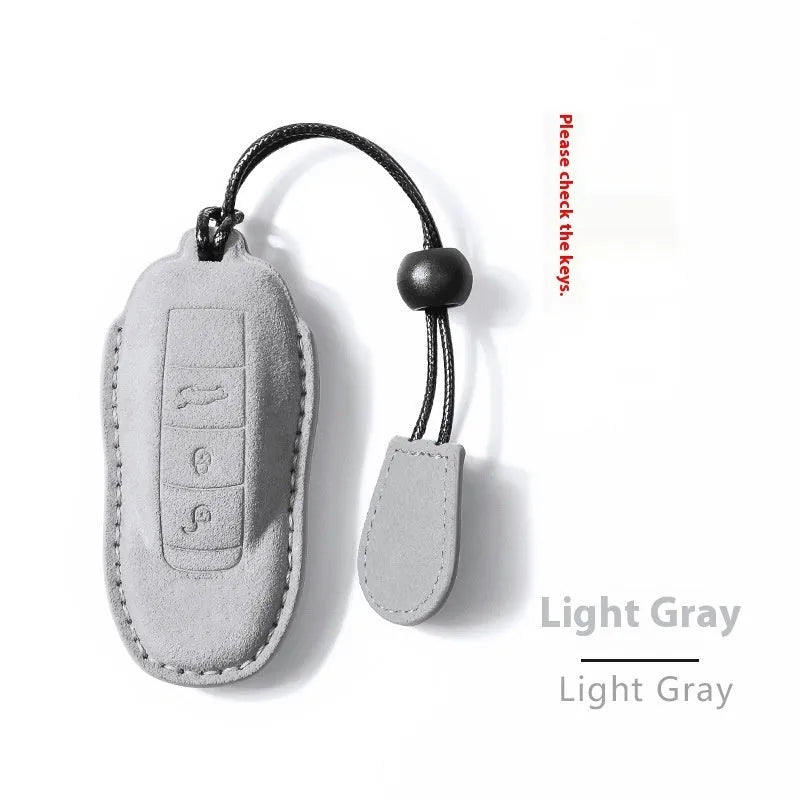 Suede car key cover in cement grey, dark green, light grey, and orange colour options.