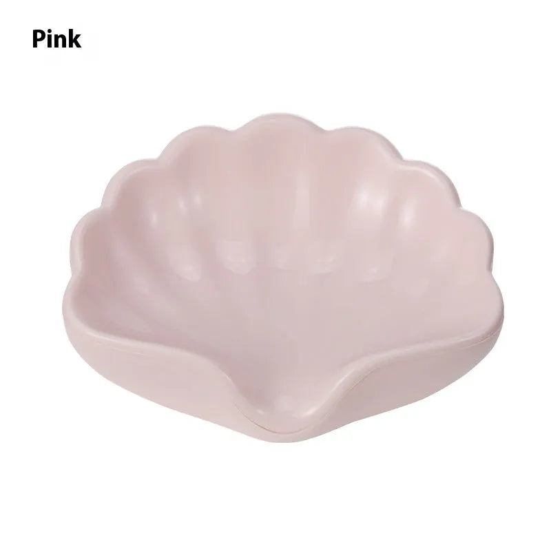 White or pink plastic shell-shaped soap dish with slatted base for bathroom use.