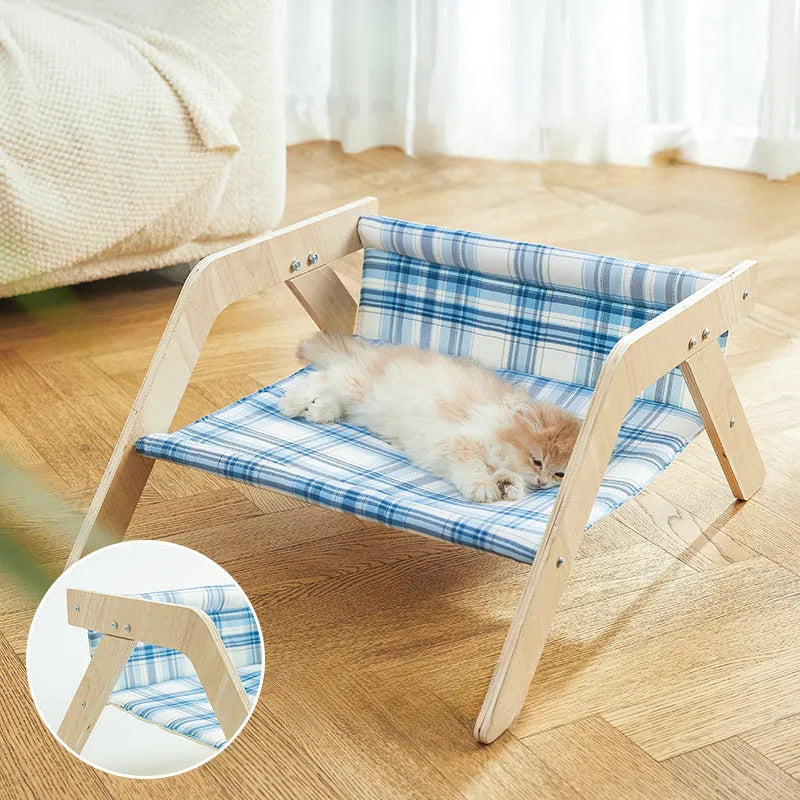 Blue elevated cat hammock bed with wooden beach chair frame on a white floor.