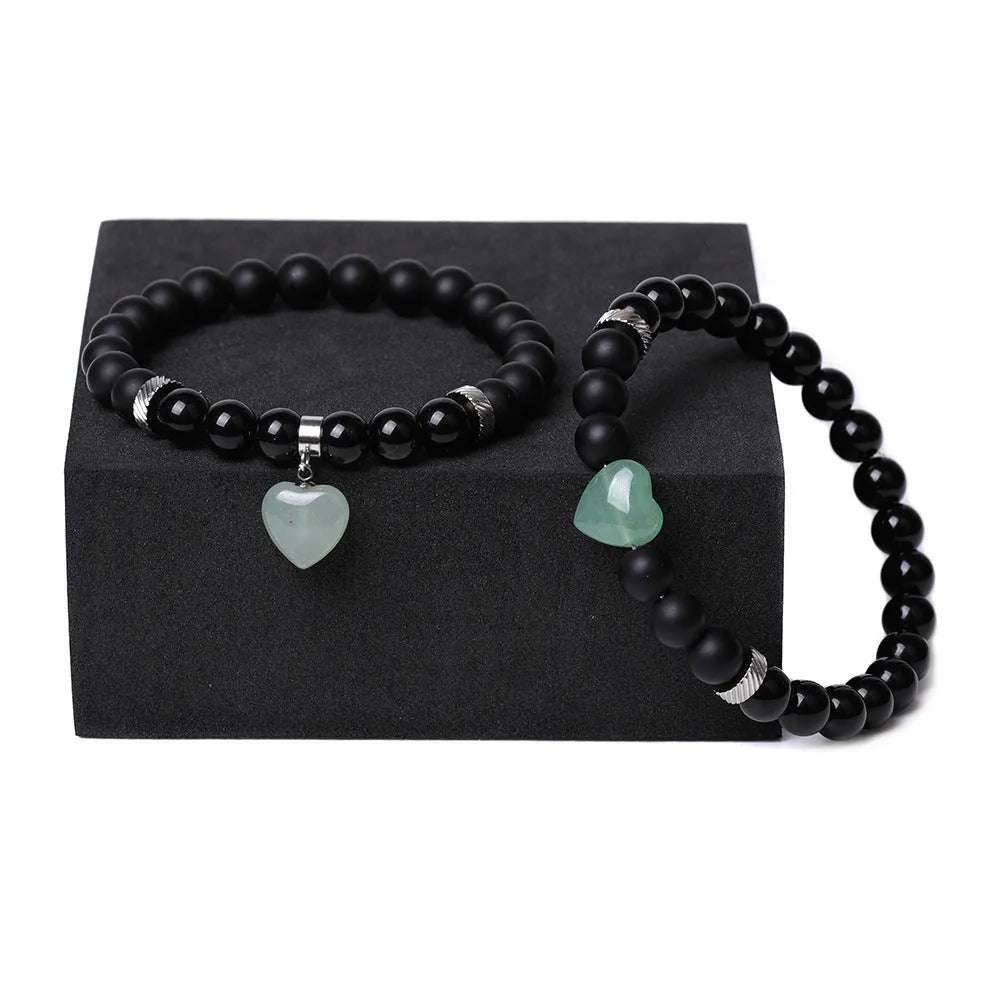 A pair of matching bracelets with polished geometric heart pendants made from natural stone.