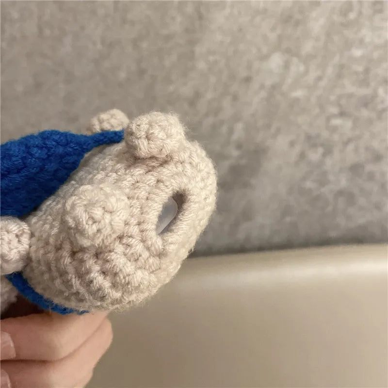 Handmade knitted koala bear backpack cover for Apple Airpods case on a table.