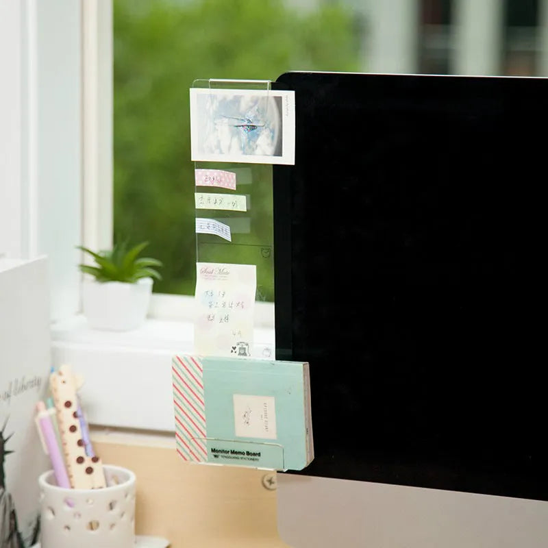 Acrylic monitor message memo board attached to monitor with wall suction, holding a post-it note