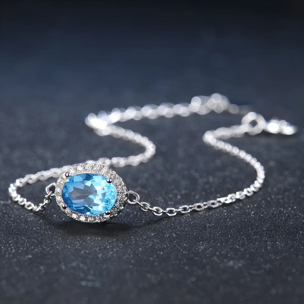 Women's 925 silver blue topaz jewellery set showing geometric earrings, ring, pendant and necklace.