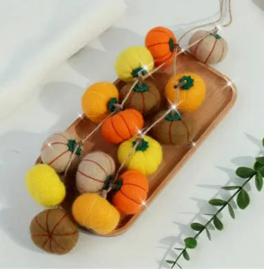 Wool felt pumpkin-shaped doll decorations in autumn colours on a neutral background