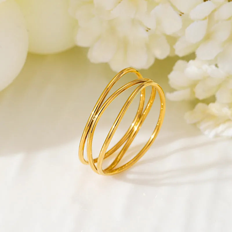 Gold-coloured titanium steel ring with a geometric three-layer coiled design on a hand.