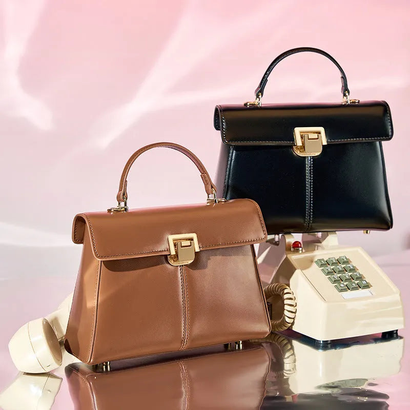 Women's black leather shoulder bag with vachette clasp showing internal compartments and adjustable strap