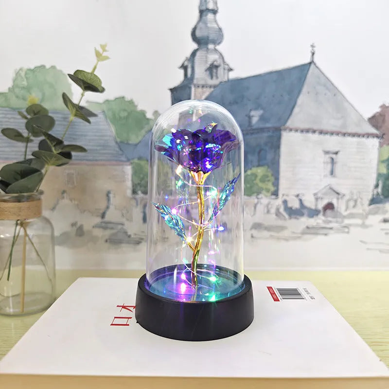 Small decorative night lamp with glass cover, plastic flower, and black base on a pink box.