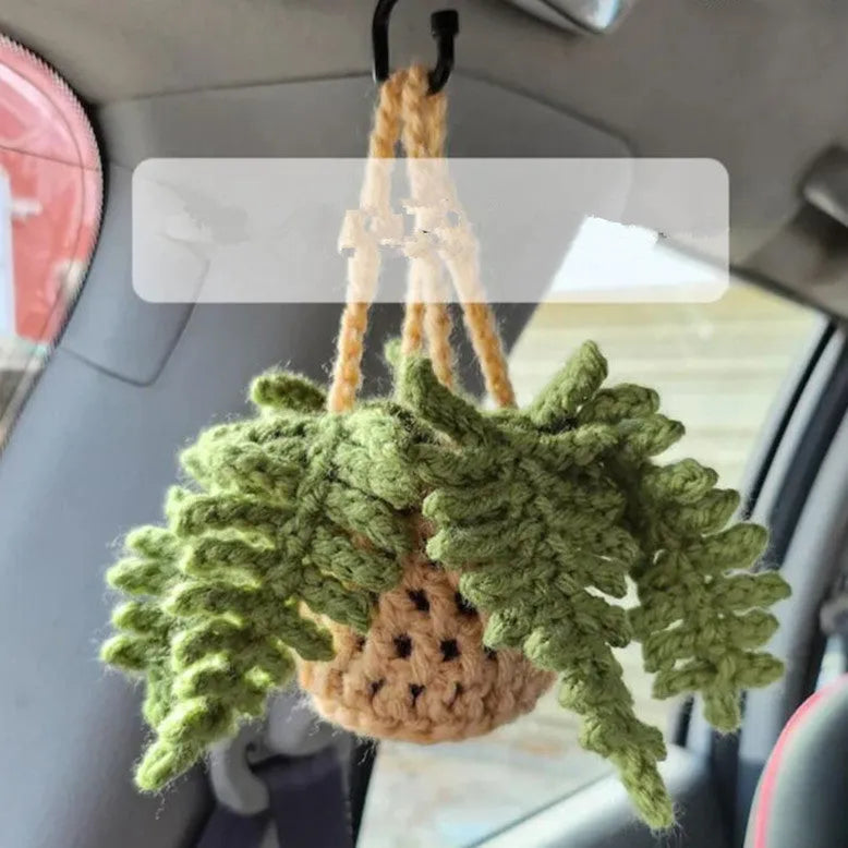 Green and white knitted wool car plant decoration with macramé texture and a white hanging rope.