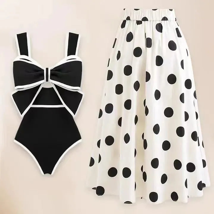 A black one-piece swimsuit for women with a white detachable skirt and a decorative bow at the front.
