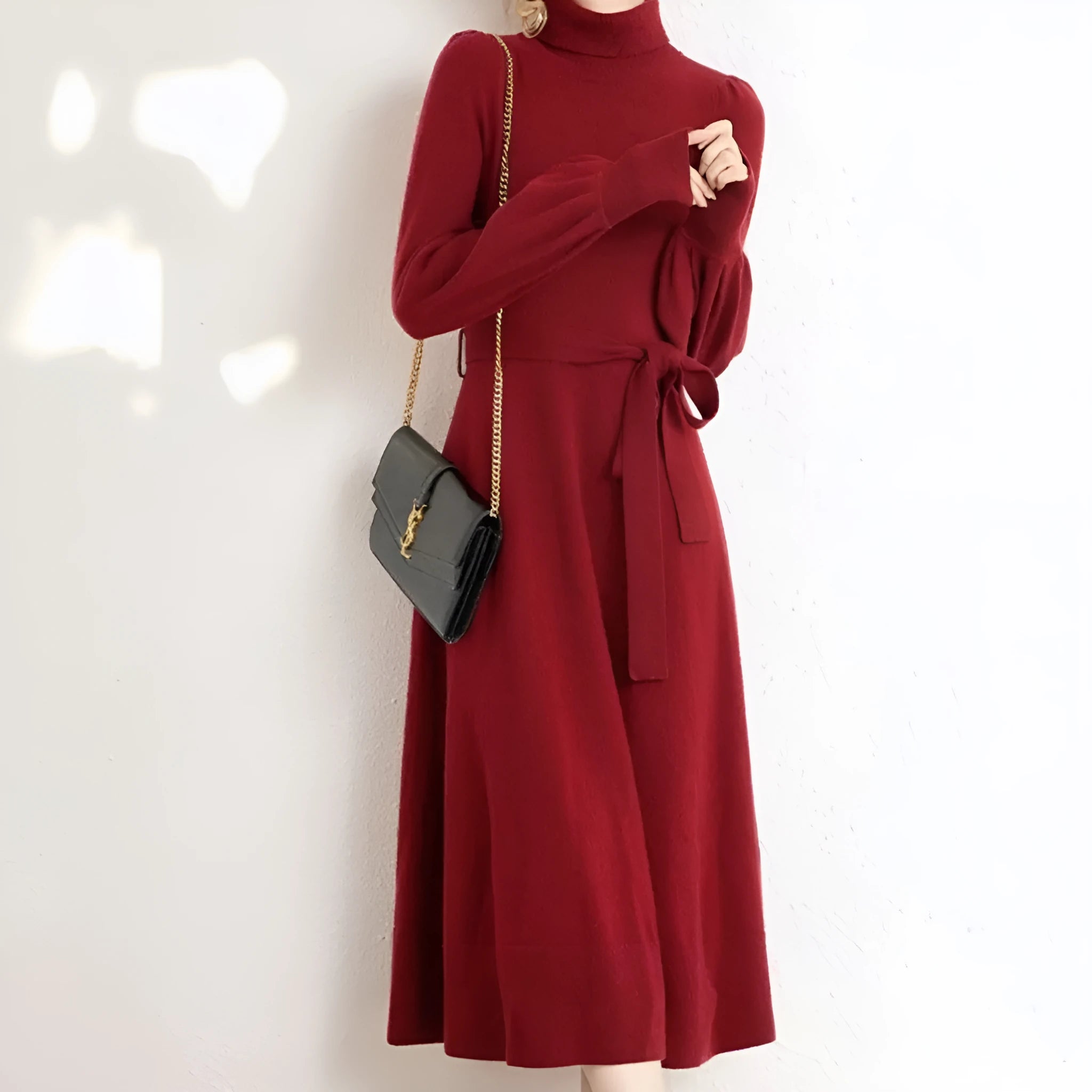A rose red turtleneck knit dress with long sleeves, an elastic waist, and a loose mid-length skirt on a hanger.