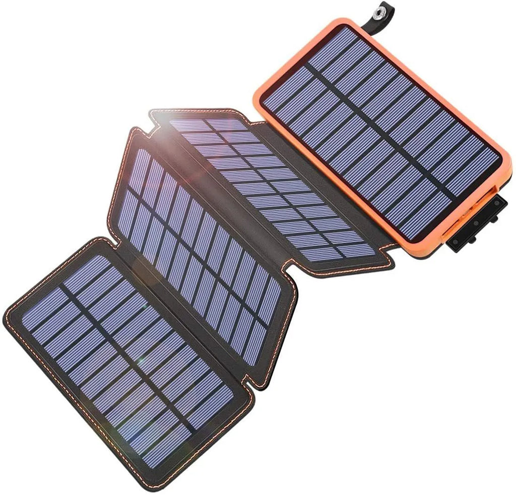 Black solar power bank with a solar panel, showing its USB ports and LED light, placed outdoors on a rock.