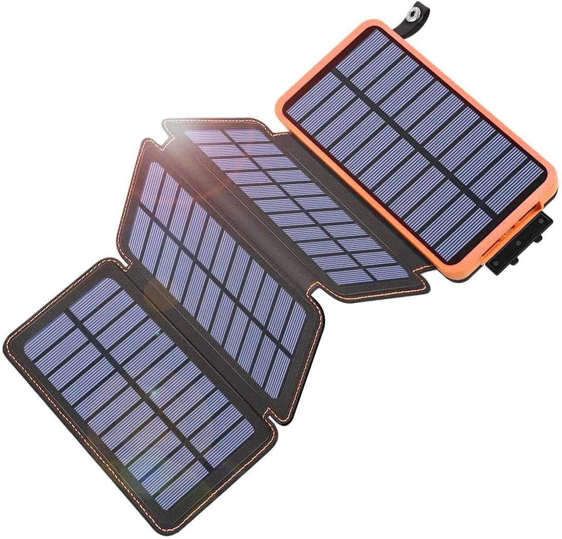 Black solar power bank with a solar panel, showing its USB ports and LED light, placed outdoors on a rock.